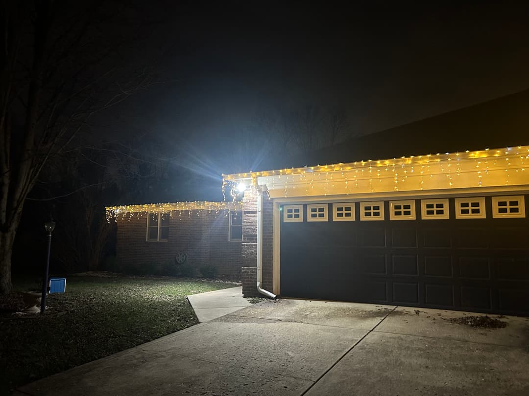 House exterior illuminated with decorative string lights at night.